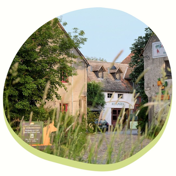 Ländlicher Hof mit Hofladen, umgeben von Feldern.