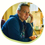 Eine Person, die telefoniert und währenddessen Notizen macht. Sie sitzt in einem Büro,