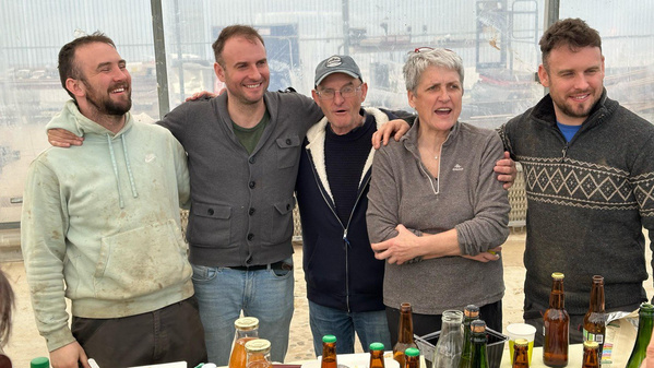 KI generiert: Gruppe von fünf Personen lächelt in einem Gewächshaus; Flaschen und Gläser stehen auf einem Tisch.