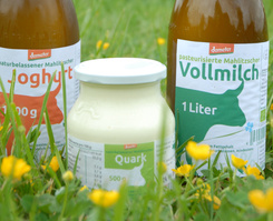KI generiert: Lebensmittel: Joghurt, Vollmilch und Quark von Demeter liegen auf einer Wiese.
