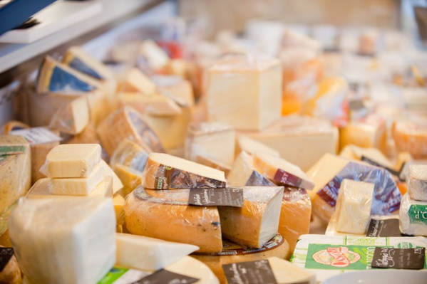 Unser Lieferfahrer Andrea steht vor einer Haustür und hält eine Kiste mit verschiedenen frischen Lebensmitteln, darunter Gemüse, Eier und eine Flasche Milch.