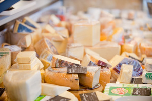 KI generiert: Verschiedene Käsesorten im Ladenregal, teils verpackt und etikettiert.