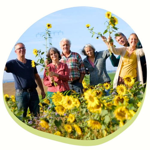 Die Betriebsgemeinschaft von Hof Mahlitzsch steht im Sonnenblumenfeld und winkt mit Sonnenblumen.